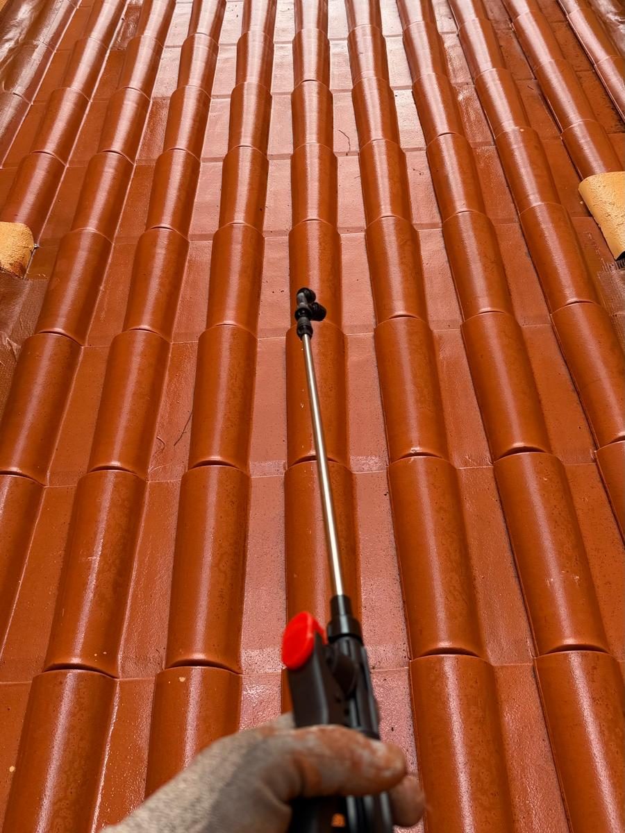 Técnico a aplicar hidrofugante com lança de pulverização sobre uma água de telha de canudo