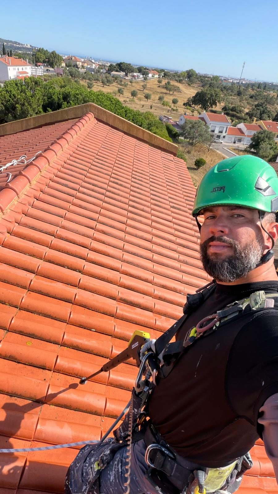 Técnico com capacete, arnês e linha de vida em cima de uma cobertura de telha cerâmica