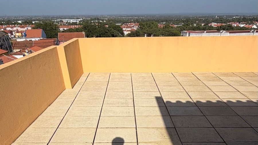 Terraço de cobertura com a lajeta já lavada, platibanda pintada e vista sobre a cidade